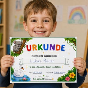 May include: A child holds a colorful certificate with the word "URKUNDE" at the top. The certificate features a koala, a swan, and floral illustrations. The text reads "Lukas M&uuml;ller" and "Gut gemacht!" (Well done!).