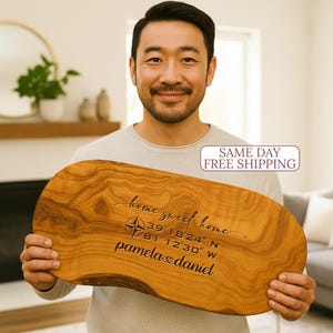 May include: A wooden cutting board with a natural wood grain pattern. The board is engraved with the words "home sweet home", coordinates, and names. The text "SAME DAY FREE SHIPPING" is also visible.