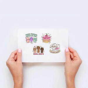 Pode incluir: Um papel branco com quatro designs de adesivos coloridos. Os adesivos incluem os textos "Period Products Should Be Free", "Girl Pwr", "Equal Rights" e "Knights for Women's Rights".