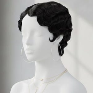 Może przedstawiać: Biała głowa manekina z czarnymi, falowanymi włosami, srebrnymi kolczykami w kształcie kół i warstwowymi naszyjnikami. Popiersie jest wystawione na czarnym marmurowym cokole, z oknem w tle.