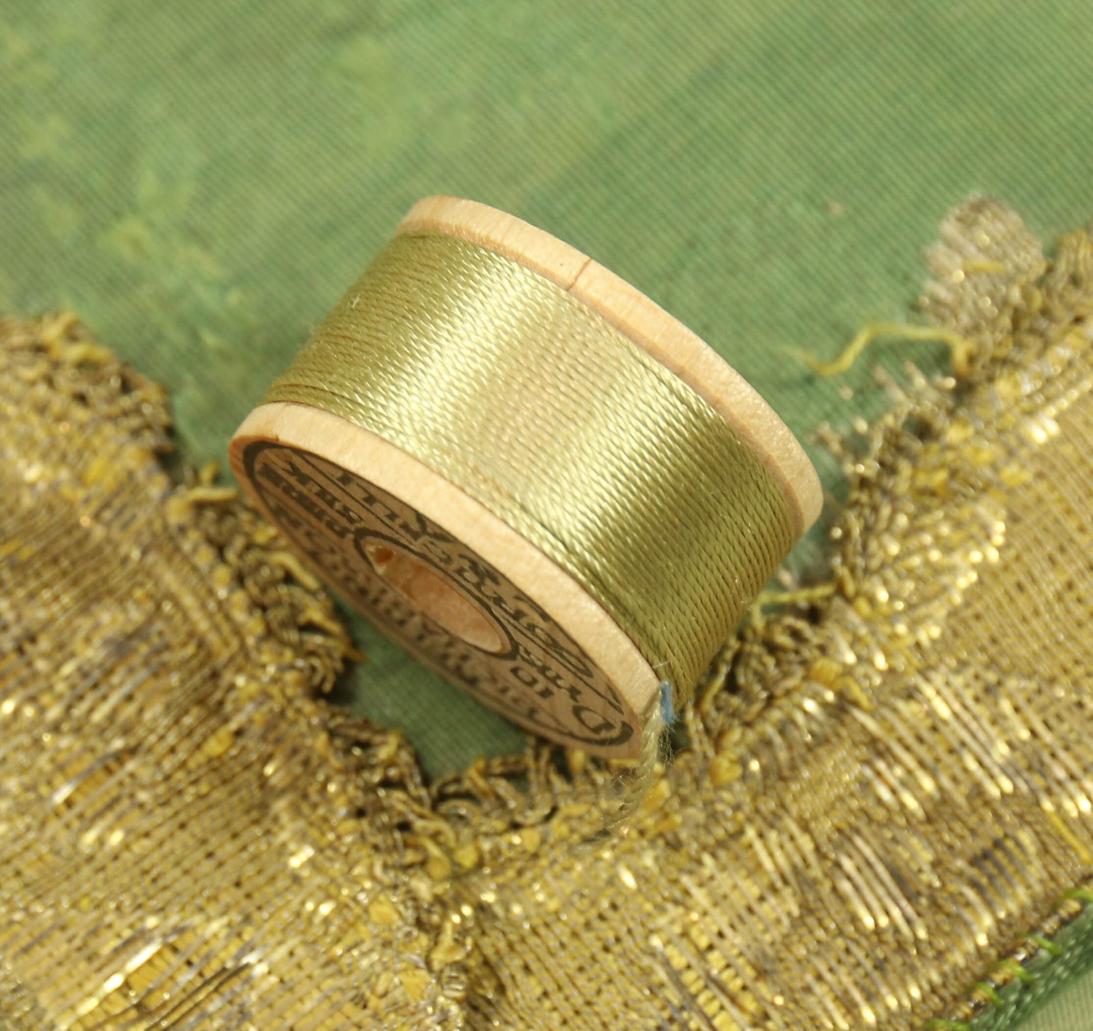 Isolated wooden spool of green thread with a needle 8414070 Stock