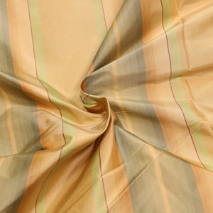 May include: Striped fabric in shades of gold, green, and brown. The fabric is woven with a subtle sheen and has a soft, drapey texture.