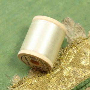May include: A wooden spool of beige silk thread with the label "BELDING'S CORticelli" and "PURE SILK" printed on it.