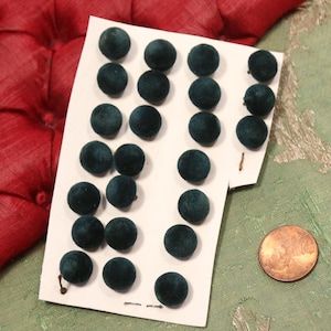 May include: A sheet of white card with 18 dark green velvet buttons. The buttons are round and have a diameter of about 1/2 inch.