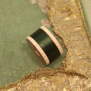 May include: A wooden spool of dark green thread.