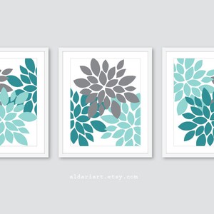May include: Three framed floral art prints. Each print features a stylized flower design in shades of gray and teal on a white background. The artwork is framed in a white border. The Etsy shop name aldariart.etsy.com is visible.