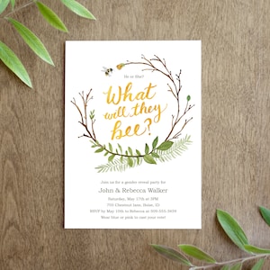 Può includere: Un invito a una festa di rivelazione del sesso con una ghirlanda ad acquerello di foglie e rami verdi. Il testo "What will they bee?" è scritto in lettere dorate. L'invito include i nomi John & Rebecca Walker, la data e l'ora della festa e l'indirizzo. Chiede inoltre agli ospiti di confermare la loro presenza entro una certa data e di indossare il blu o il rosa per votare.