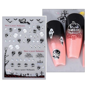 May include: A sheet of Halloween-themed nail decals featuring black and white designs of skulls, ghosts, bats, and tombstones, with text reading Have a great Halloween, Happy Halloween, and Trick or Treat, shown applied to two pink and black nails.