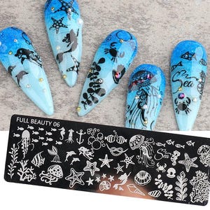 Può includere: Nail art blu e bianco con disegni a tema marino, tra cui delfini, meduse e stelle marine. Le unghie sono decorate con strass. Una piastra di metallo nero con contorni di varie creature marine è in primo piano. Il testo sulla piastra recita "FULL BEAUTY 06".