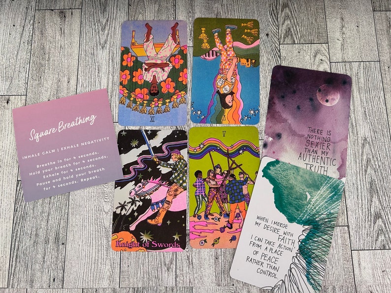 May include: Five tarot cards with colorful illustrations and text. The cards are laid out on a wooden surface. The text on the cards includes "Knight of Swords", "There is nothing sexier than my authentic truth", "When I merge my desire with faith, I can take action from a place of peace rather than control", and "Square Breathing: Inhale Calm | Exhale Negativity".