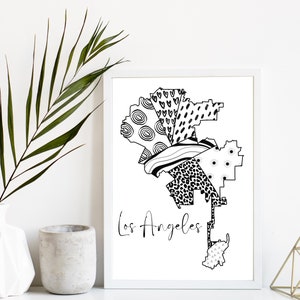 May include: Black and white line art print of the Los Angeles city map with a variety of patterns and textures. The print is framed in a white frame and is displayed on a white wall.