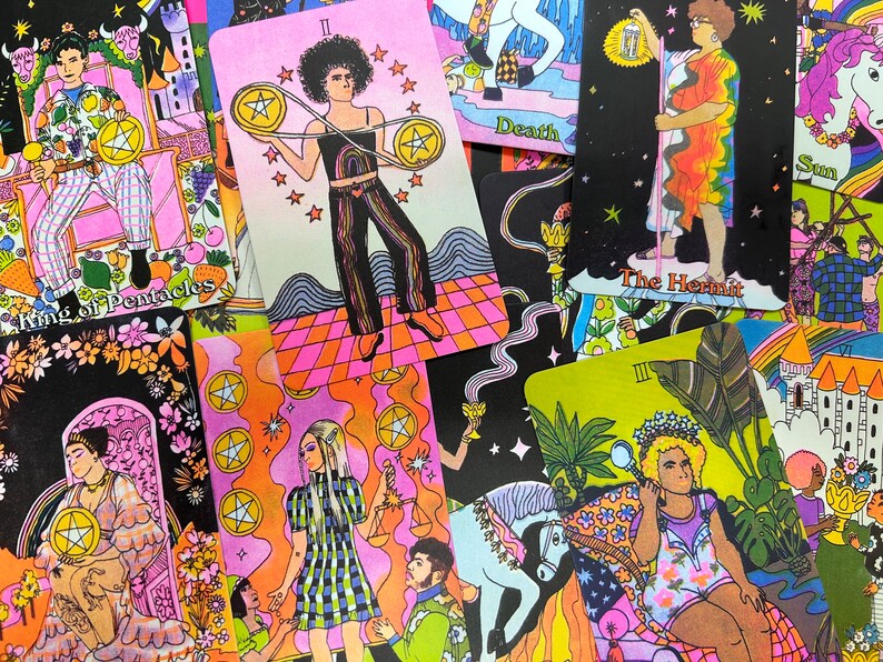 May include: A colorful set of tarot cards featuring illustrations of people in various poses. The cards are arranged in a random order, with some cards partially visible. The cards are printed on a white background with black outlines. The cards feature a variety of colors, including pink, blue, green, yellow, and orange.