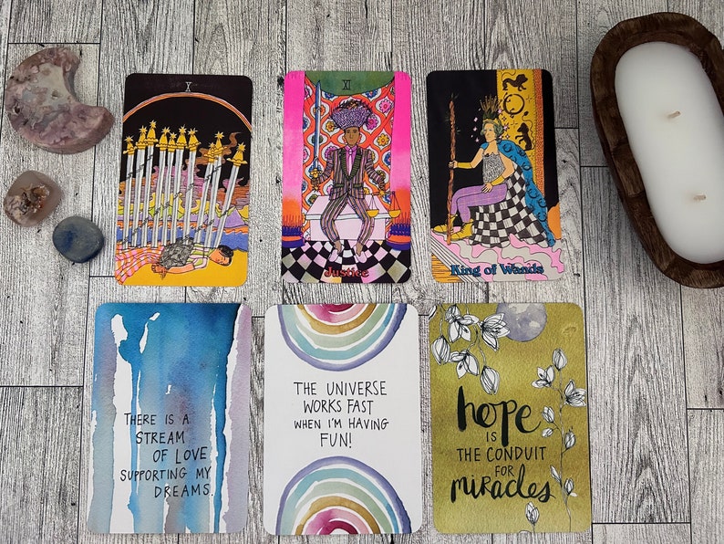 May include: A set of ten tarot cards with colorful illustrations and text. The cards include the following text: "There is a stream of love supporting my dreams", "The universe works fast when I'm having fun!", "Hope is the conduit for miracles", "King of Wands", "Justice", and "Ten of Swords".