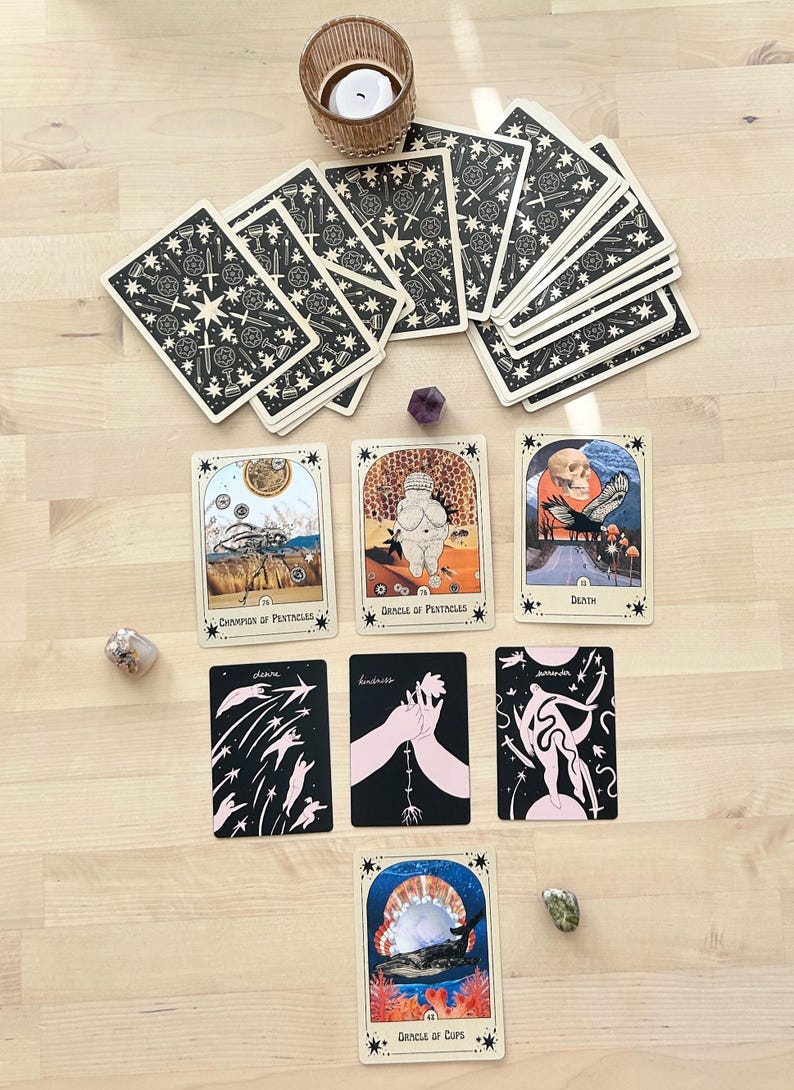 May include: Tarot card spread with 10 cards laid out on a wooden surface. The cards include: Champion of Pentacles, Circle of Pentacles, Death, Stars, Lovers, Surrender, Circle of Cups, and a deck of cards with a star and sword design.