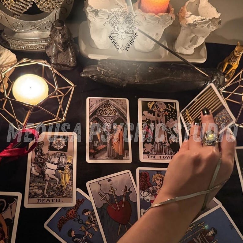 May include: A collection of tarot cards with various illustrations, including a card labeled "DEATH." The cards are arranged on a black surface, alongside a lit candle in a geometric holder and other decorative items. The image has a mystical theme.