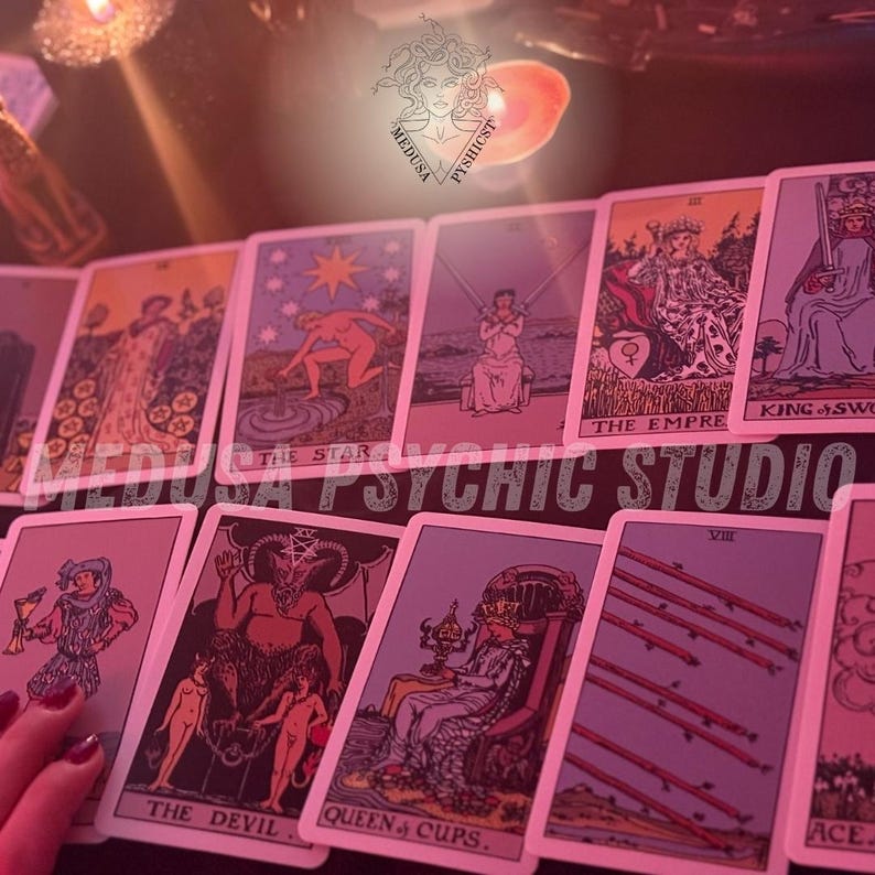 May include: A collection of tarot cards with various illustrations and titles, including "The Star," "The Devil," and "Queen of Cups." The cards are arranged on a dark surface, with the text "MEDUSA PSYCHIC STUDIO" visible. The color scheme is predominantly pink and purple.
