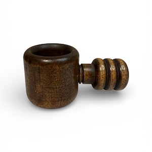 May include: A wooden nutcracker with a dark brown finish. The nutcracker has a cylindrical body and a handle with a series of rounded ridges. The design is simple and classic, suitable for cracking various nuts.