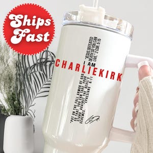 May include: White tumbler with a handle and a clear lid. The tumbler has the text "I AM CHARLIEKIRK" in red, along with Bible verses. A red circle with the words "Ships Fast" is in the upper left corner.