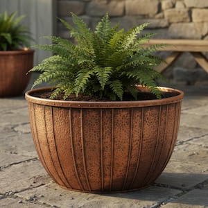 May include: A large, copper-colored planter with a hammered texture and vertical rivet detailing. The planter is filled with soil and a lush green fern. The design is reminiscent of a barrel, perfect for outdoor decor.