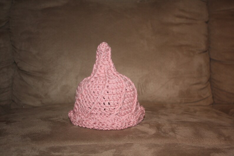 Puede incluir: Un gorro de punto de color rosa con una parte superior puntiaguda y un dise&ntilde;o texturizado.