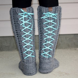 May include: Gray crocheted boots with blue ribbon laces. The boots are tied in a criss-cross pattern up the leg.