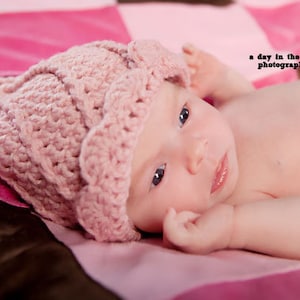 May include: A painting depicting a seascape with a city skyline in the distance. The sky is a soft yellow and pink, and the water is a light blue. There are people walking on the beach in the foreground.