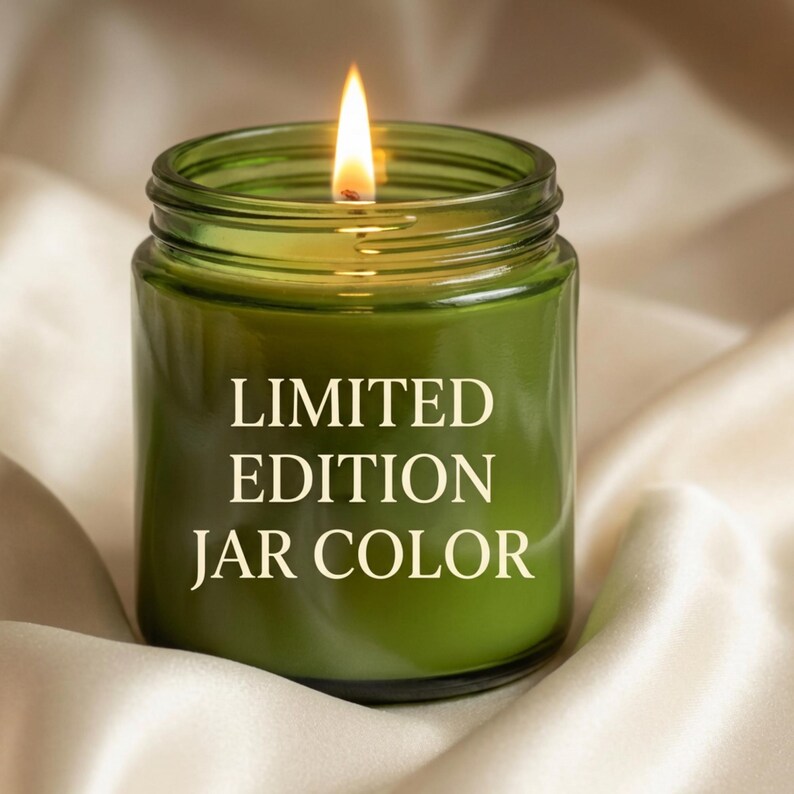 K&ouml;nnte beinhalten: Eine brennende gr&uuml;ne Kerze im Glas mit dem Text "LIMITED EDITION JAR COLOR" in Wei&szlig;. Die Kerze befindet sich in einem durchsichtigen Glas. Der Hintergrund ist ein weicher, cremefarbener Stoff.