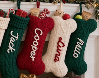 May include: Six hanging Christmas stockings in red, cream, and green cable knit patterns. Four are traditional boot-shaped with names Mom, Bella, Jack, and Cooper. Two are bone-shaped with names Luna and Milo. Each features a folded cuff and hanging loop.
