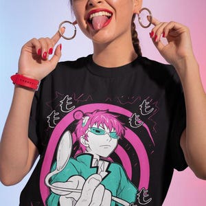 May include: Black t-shirt featuring a graphic of an anime character with pink hair and teal glasses. The character is holding a spoon. The text "The Disastrous Life of Saiki K" is at the bottom of the shirt.