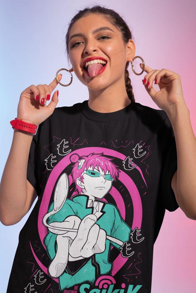 May include: Black t-shirt featuring a graphic of an anime character with pink hair and teal glasses. The character is holding a spoon. The text "The Disastrous Life of Saiki K" is at the bottom of the shirt.