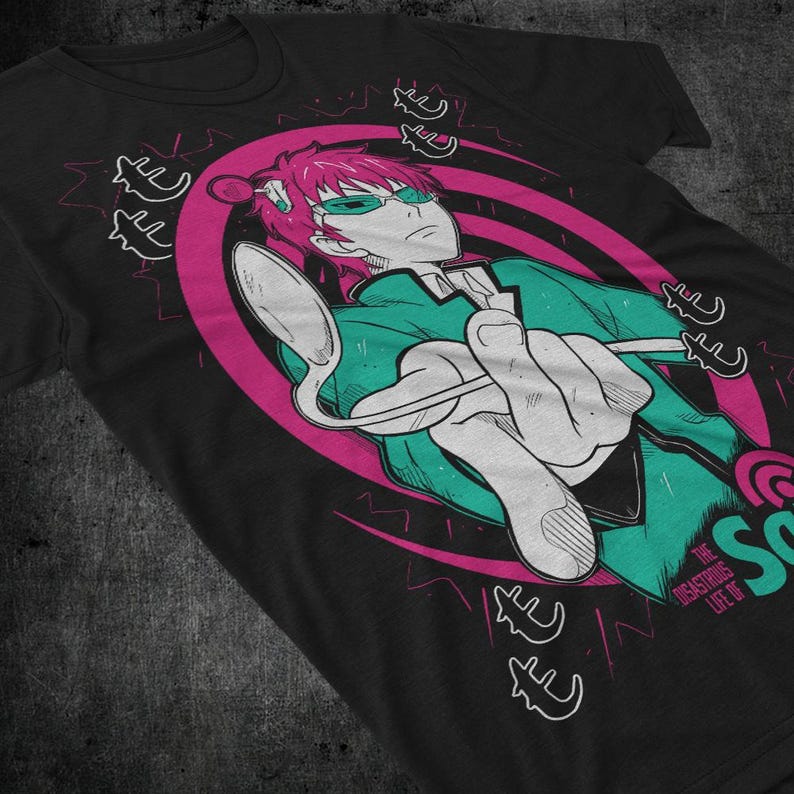 May include: Black t-shirt featuring a graphic of an anime character with pink hair and green glasses holding a spoon. The design includes a pink and white oval, lightning bolts, and text that reads "The Disastrous Life of Saiki K."