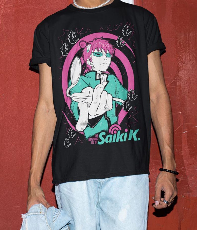 May include: Black t-shirt featuring a graphic of an anime character with pink hair and green glasses, holding a spoon. The design includes pink and white swirls and Japanese text. The text "Saiki K." is also visible.
