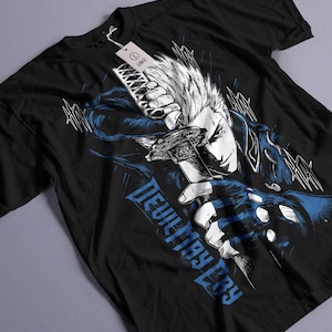 Puede incluir: Una camiseta negra de manga corta con una ilustración gráfica de un personaje con pelo de punta sosteniendo una katana. El diseño incluye detalles en azul y blanco y el texto "DEVIL MAY CRY" en azul. Tiene una etiqueta blanca con "LARGE" adjunta.
