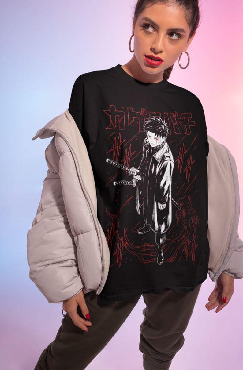 May include: Black t-shirt featuring a detailed anime-style illustration of a character holding two swords, with red Japanese text and accents. The design is set against a backdrop of red lines. The shirt is worn by a person.