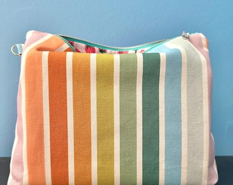 Estuche o bolsa de viaje con cremallera y estampado de rayas arcoíris.