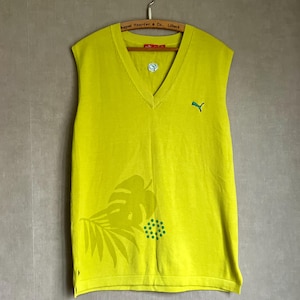 May include: A lime green sleeveless V-neck sweater vest featuring a small embroidered green leaping cat logo on the left chest. The lower front displays a tonal leaf pattern and a small cluster of green dots. It is displayed on a wooden hanger.