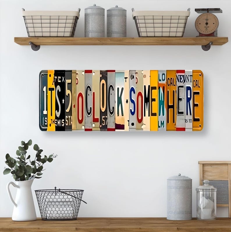 May include: A metal sign made of repurposed license plates spelling out "It's 5 o'clock somewhere". The sign is hanging on a shelf above a kitchen counter.