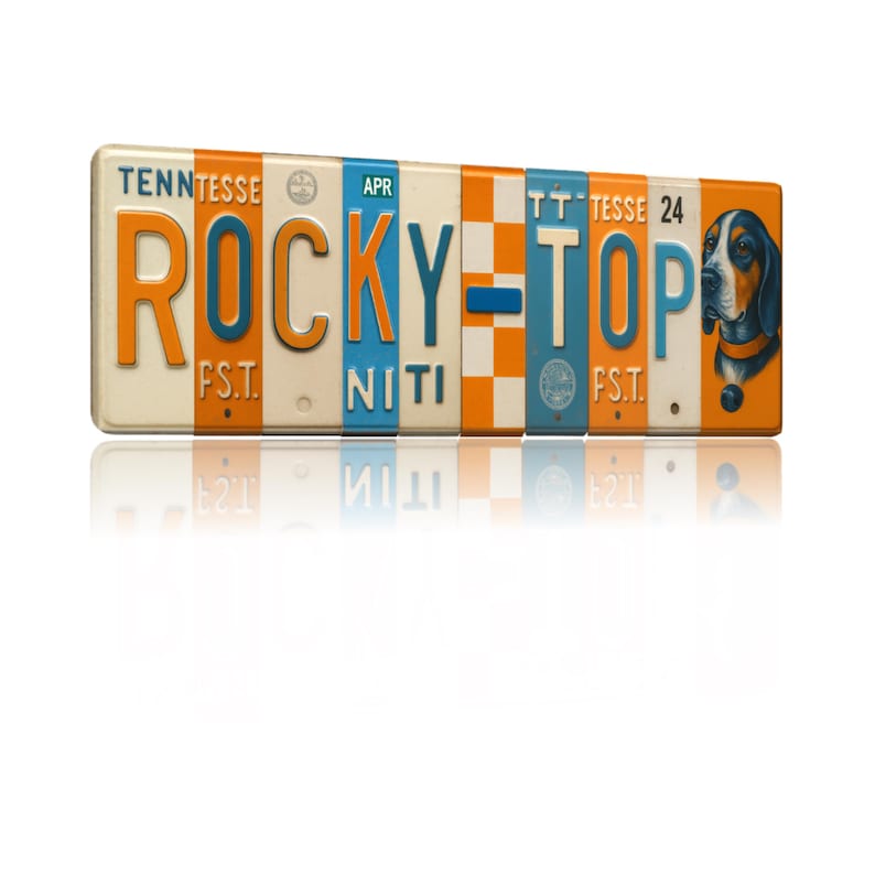 K&ouml;nnte beinhalten: Rechteckiges Schild mit den Worten "ROCKY TOP" in orangefarbenen und blauen Buchstaben. Das Schild hat ein Vintage-Kennzeichen-Design mit einer Illustration eines Jagdhundes auf der rechten Seite. Das Schild ist cremefarben mit orangefarbenen und blauen Akzenten.