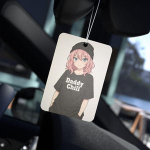 Può includere: Profumatore per auto rettangolare con un'illustrazione in stile anime di una persona con capelli rosa, occhi blu e un berretto nero. La persona indossa una maglietta nera con la scritta "Daddy Chill". Il profumatore è appeso a un filo bianco.