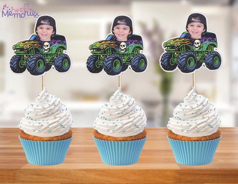 May include: Three cupcakes with blue liners and white frosting, each topped with a monster truck image featuring a child's face. The monster trucks are green, black, and orange with skull details. The cupcakes sit on a wooden surface.