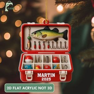 May include: A red and white fishing tackle box Christmas ornament. The ornament features a detailed illustration of a fish, fishing lures, and hooks. The text "MARTIN 2025" is displayed on the front, with the text "2D FLAT ACRYLIC NOT 3D" below.