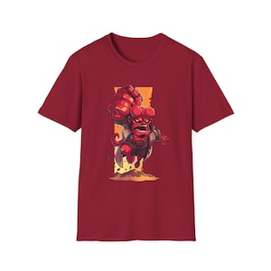 May include: Red t-shirt with a cartoon illustration of a red devil character with horns and a goatee. The character is wearing a brown coat and is punching forward. The background is a yellow and orange color.