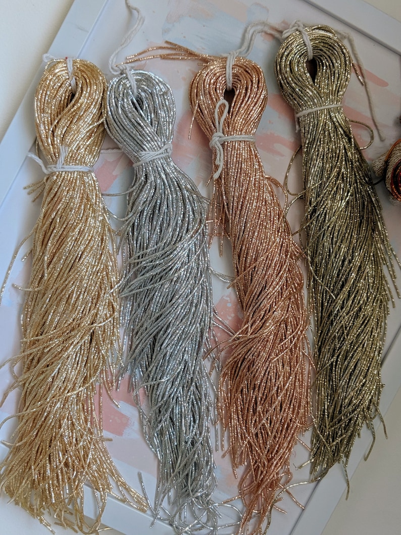 May include: Four spools of metallic seed beads in gold, silver, rose gold, and green.
