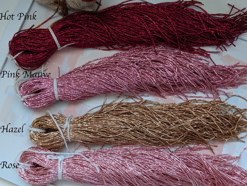 May include: Four spools of metallic seed beads in different colors: hot pink, pink mauve, hazel, and rose. The beads are arranged in a row, with the hot pink beads at the top and the rose beads at the bottom.