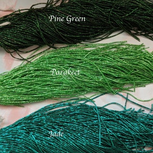 May include: Three strands of green glass seed beads, labeled "Pine Green", "Parakeet", and "Jade".