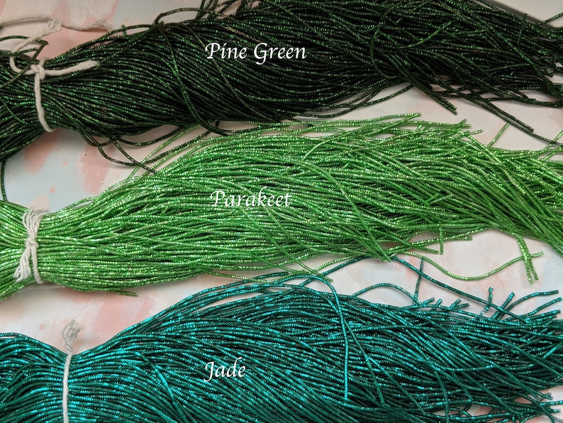 May include: Three strands of green glass seed beads, labeled "Pine Green", "Parakeet", and "Jade".