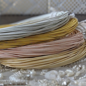 May include: Four spools of metallic wire in silver, gold, rose gold, and a lighter gold color. The spools are stacked on top of each other.
