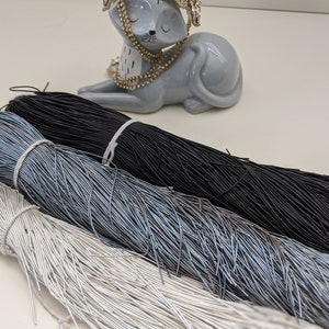 May include: Three spools of cord, one black, one silver, and one light blue. The cords are made of thin, flexible strands.