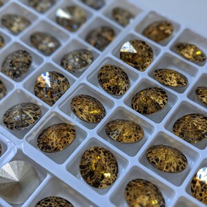 May include: A close-up of a tray of gold and black rhinestones. The rhinestones are arranged in a grid pattern and have a leopard print design.