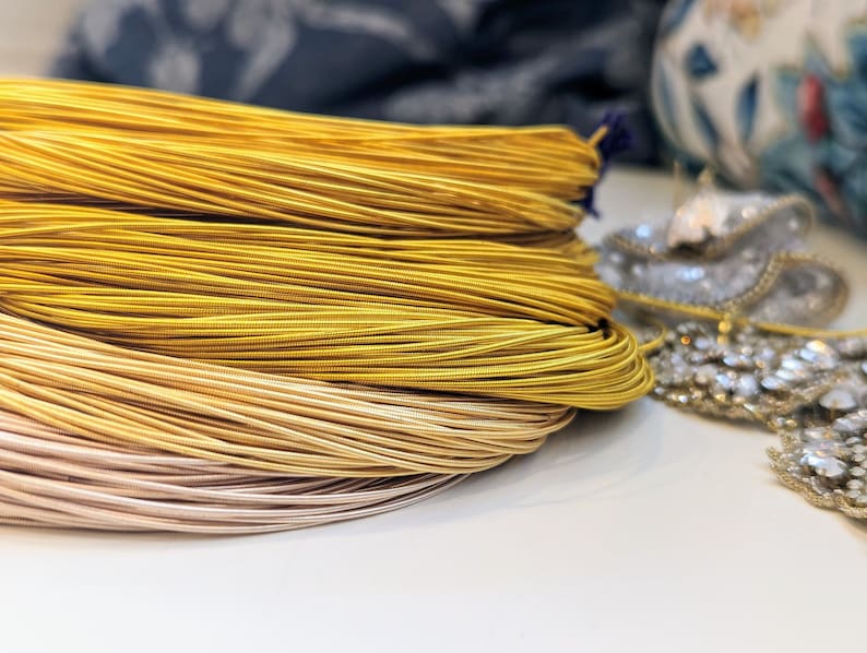 May include: A close-up of a pile of gold and beige cord, likely used for jewelry making or crafting.
